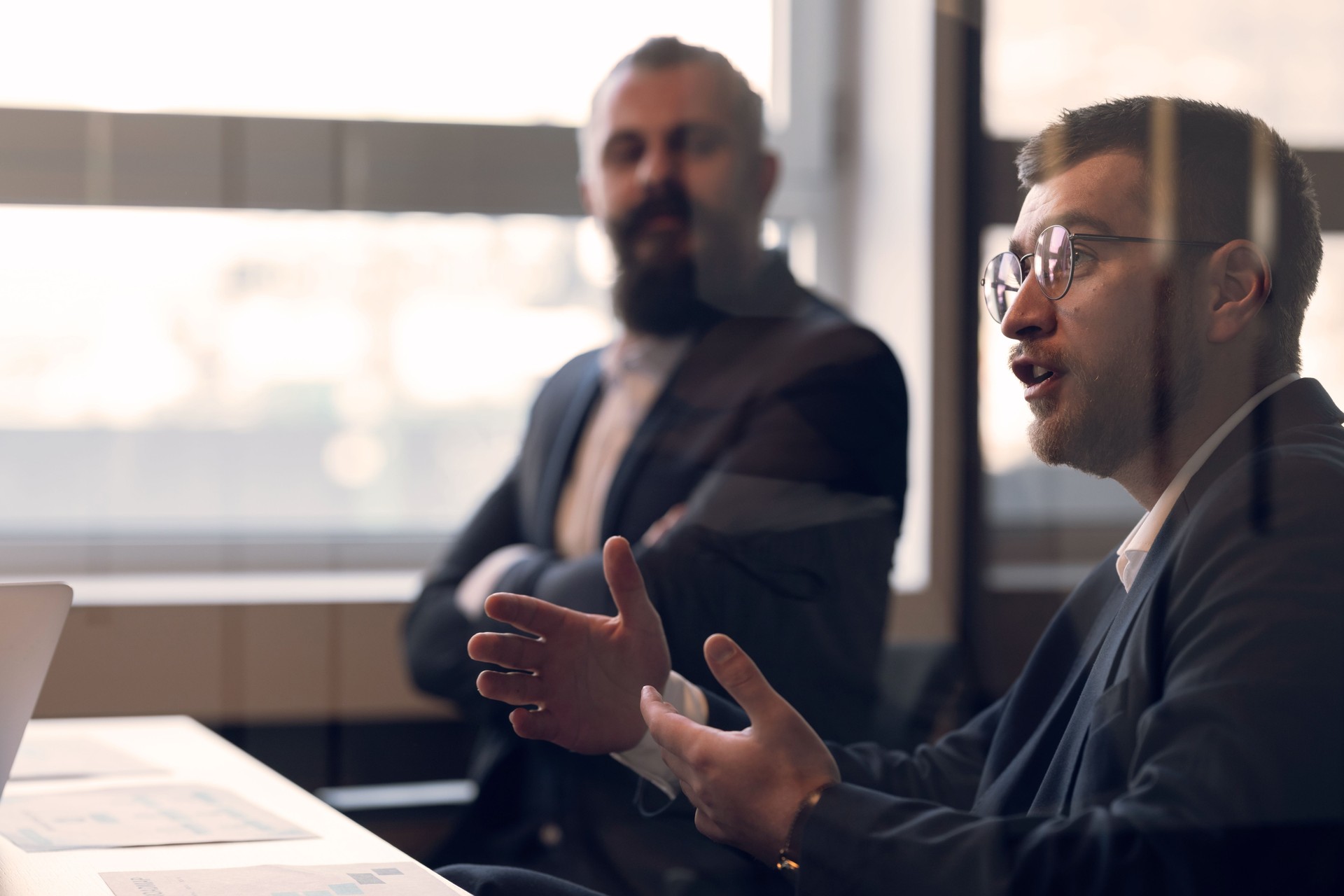 Business meeting discussion with two professionals in a modern office setting. Concept of corporate communication, decision-making, leadership, and teamwork in a professional environment.